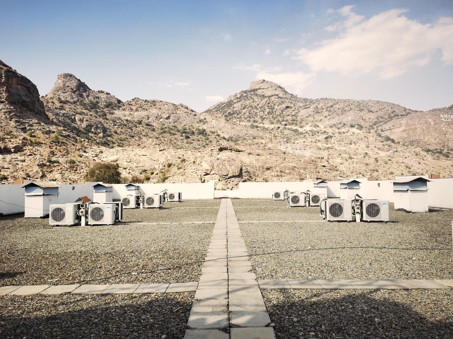 Rooftop air conditioning units in front of dry rocky hills under a blue sky
